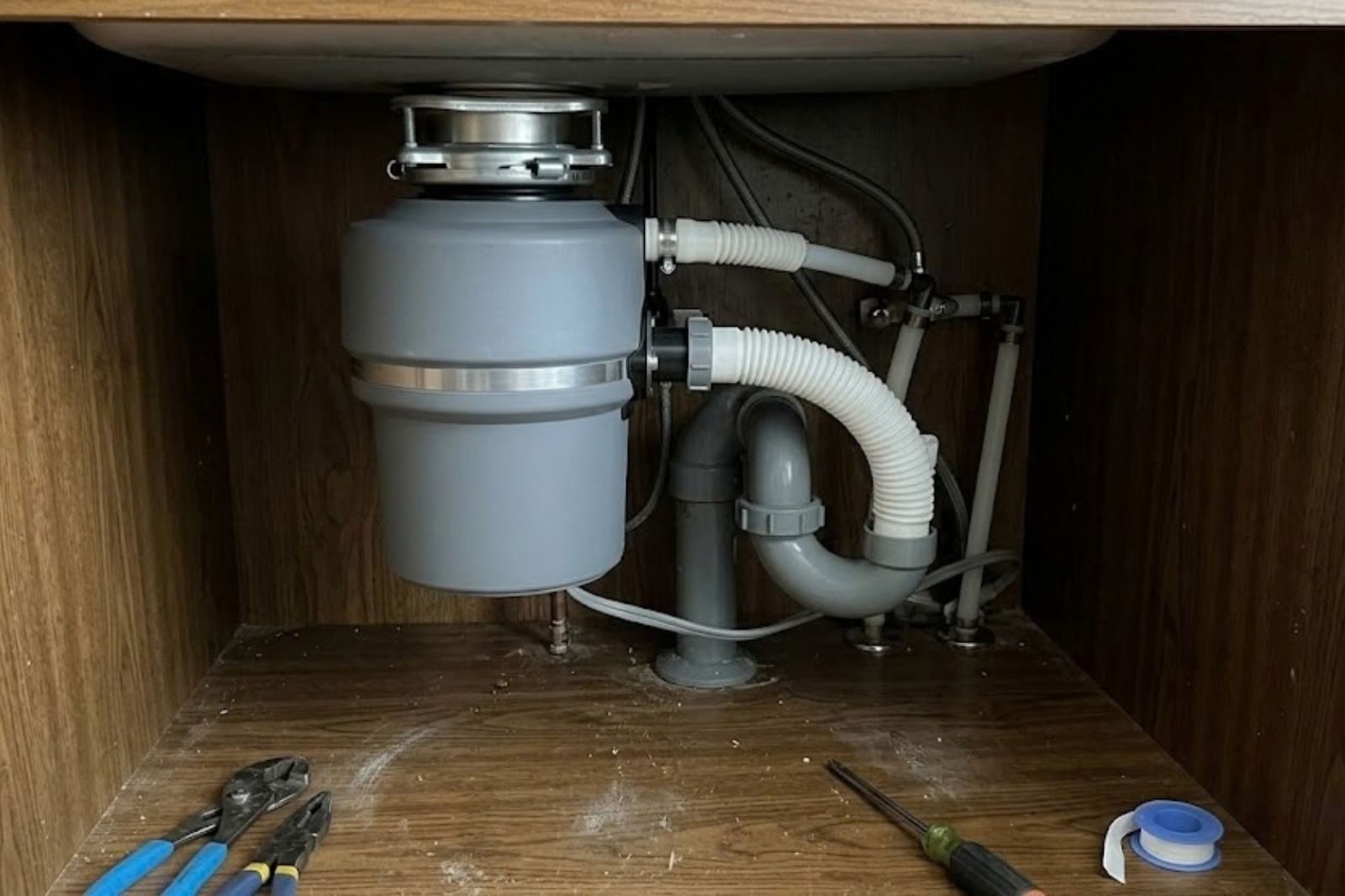 Plumber repairing a garbage disposal under a kitchen sink in Fort Myers, FL